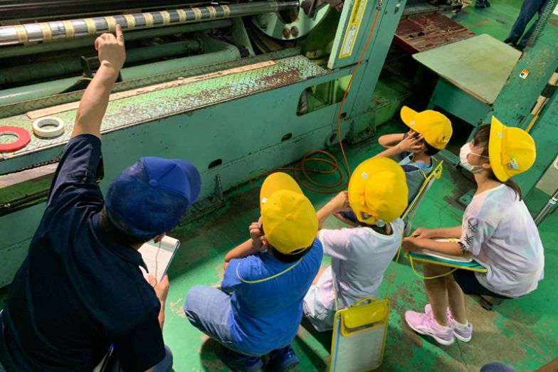 工場の説明する社員と見学する子どもたち