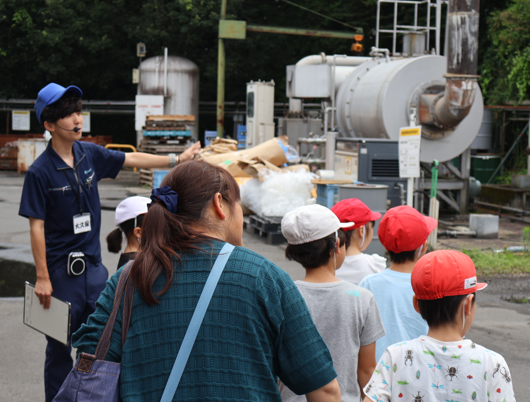 工場の説明する社員と見学する子どもたち